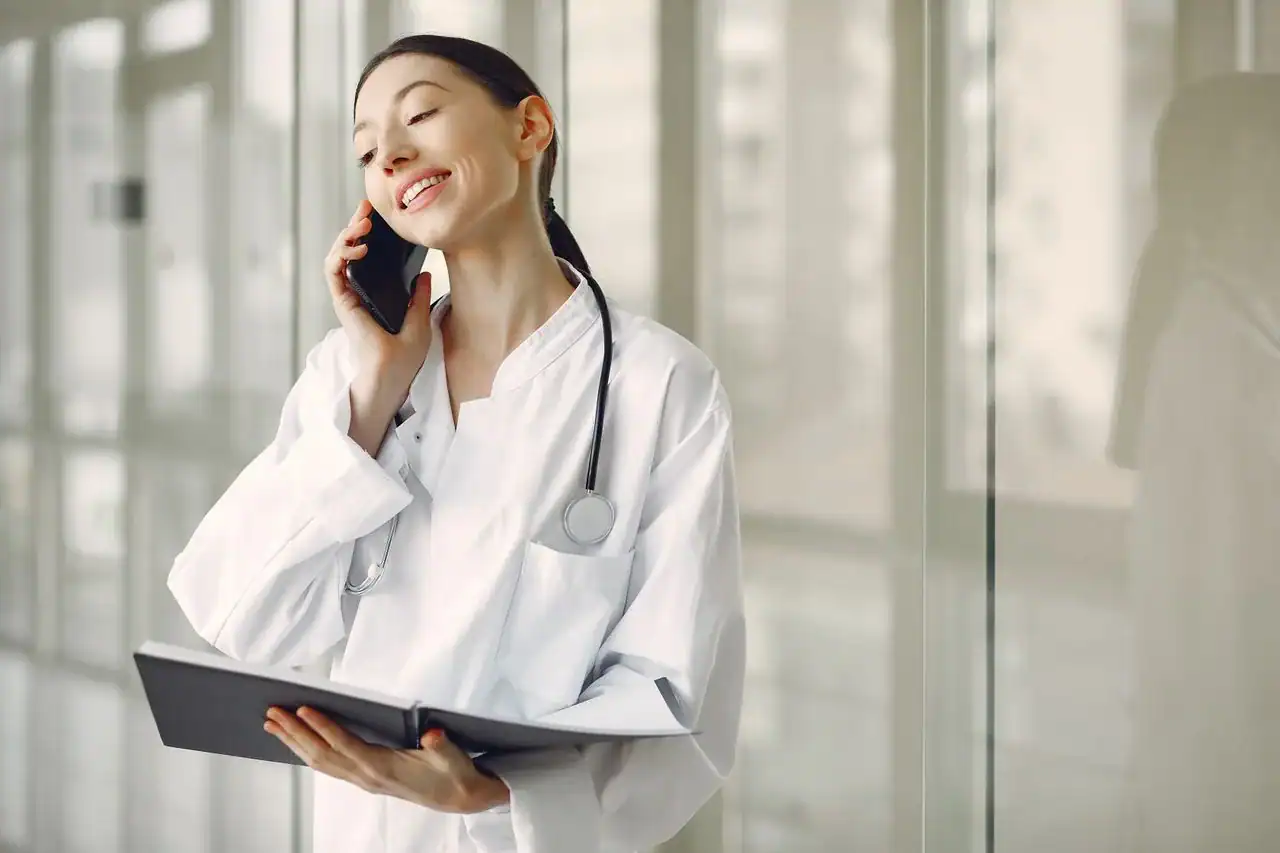 Médecin du centre SNP au téléphone avec un confrère hospitalier, dossier patient ouvert, ambiance de coordination professionnelle