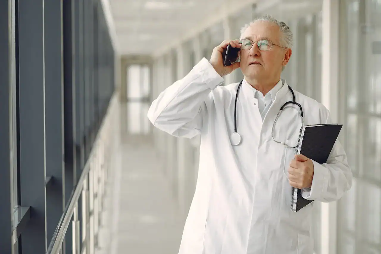 Médecin au téléphone dans son centre SNP en soirée, salle d'attente vide en arrière-plan, ambiance de fin de journée calme