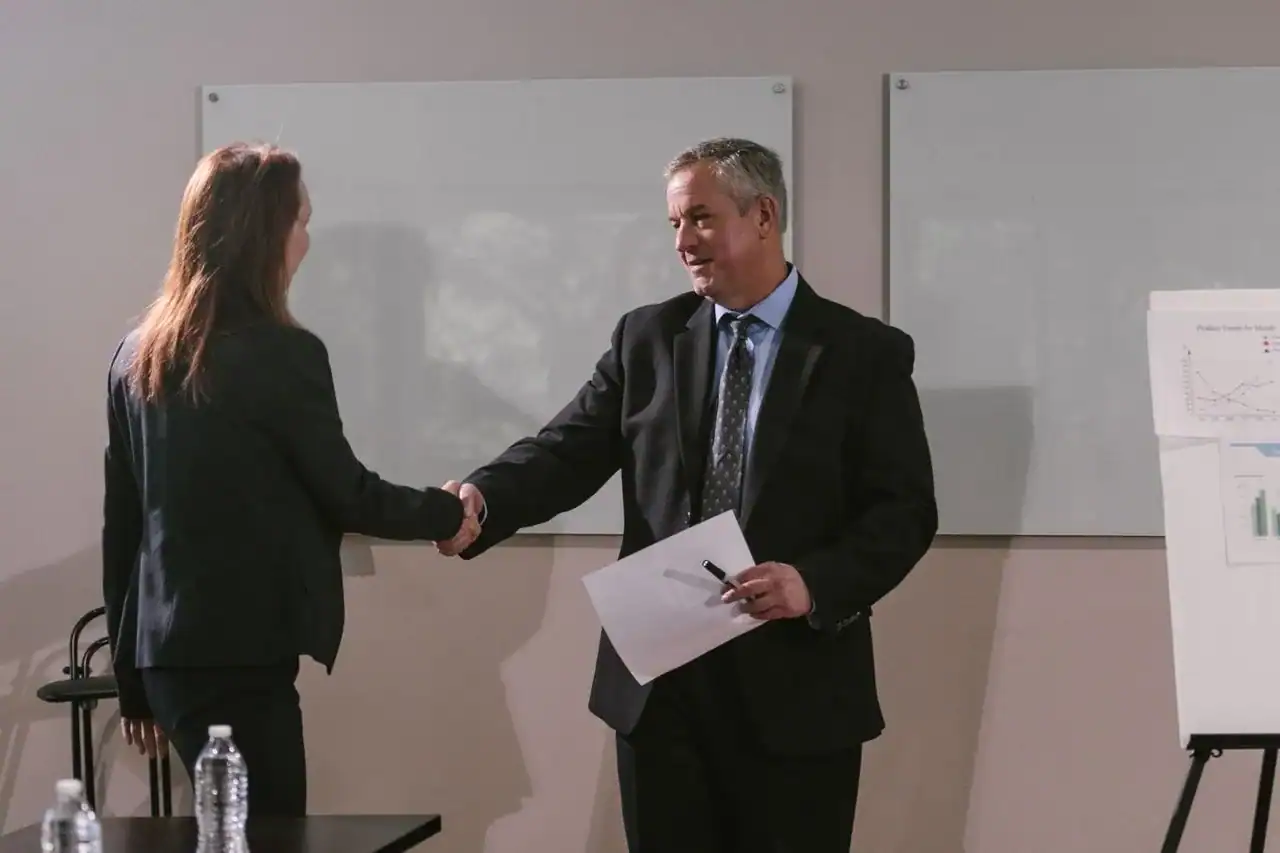 Médecin serrant la main d'un confrère généraliste dans un couloir médical, ambiance de rencontre professionnelle cordiale, éclairage naturel