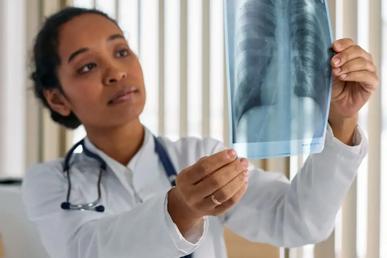 Médecin interprétant une radiographie numérique dans un centre de soins non programmés — qualification clinique des cas grâce au plateau technique