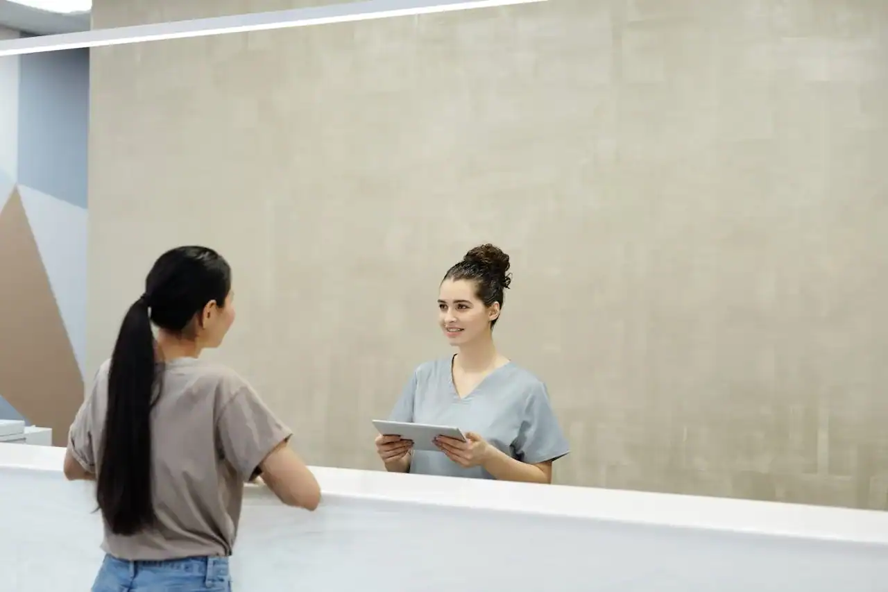 Médecin remplaçant arrivant dans un centre SNP, accueilli par la secrétaire médicale qui présente le logiciel, ambiance matinale professionnelle