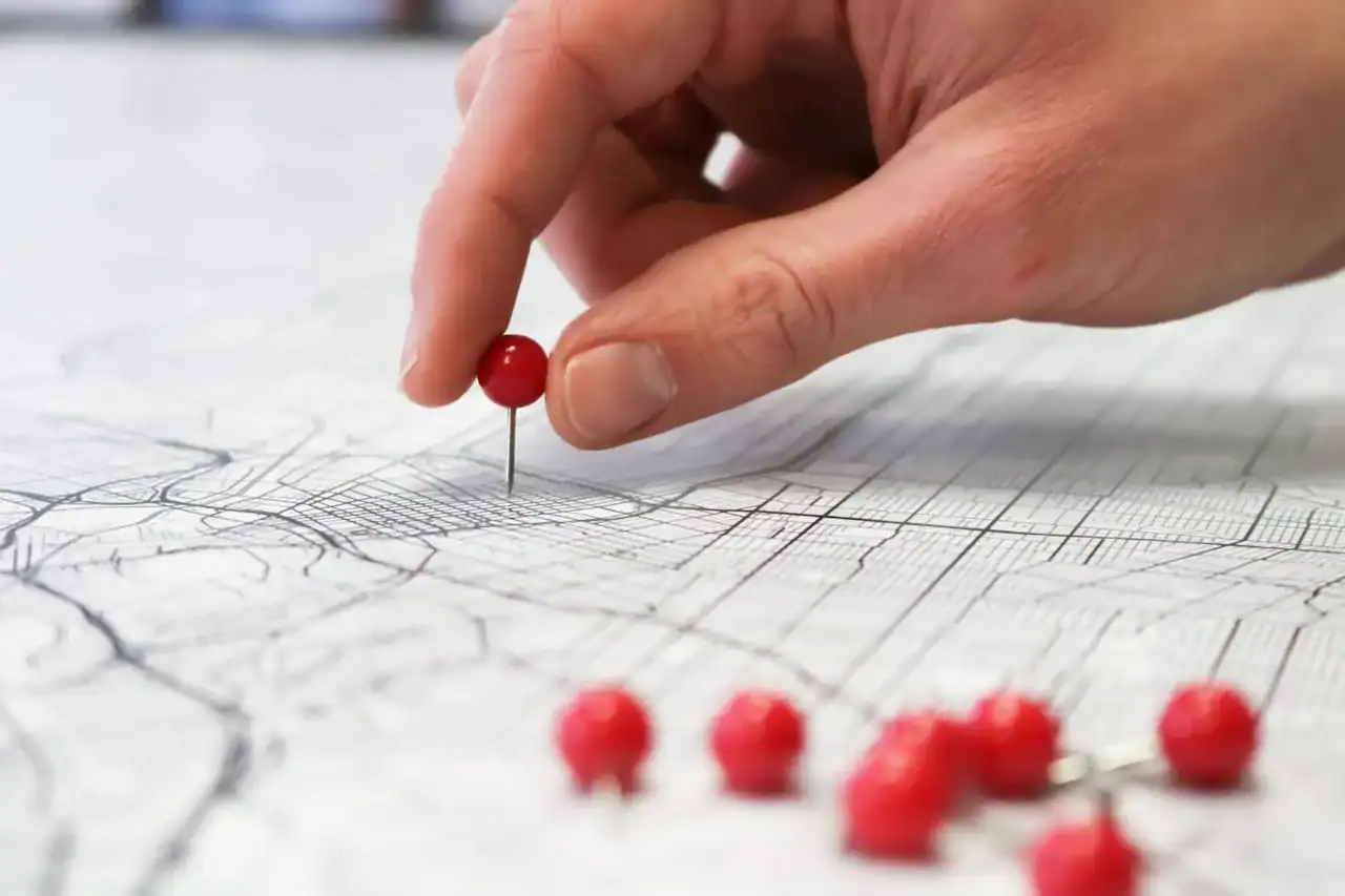 Médecin fondateur devant une carte de territoire avec deux épingles marquant deux sites distincts, ambiance bureau stratégique