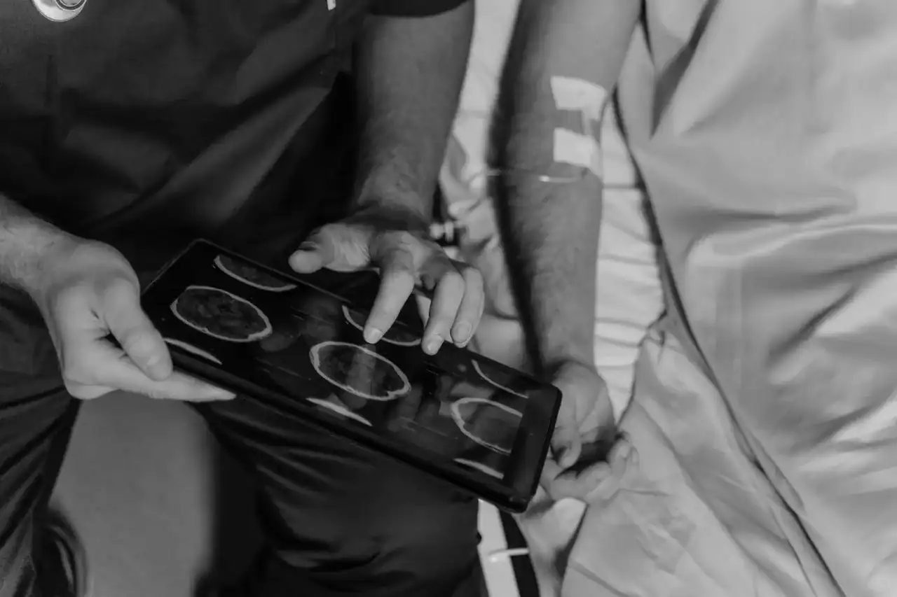 Médecin de centre SNP regardant une image clinique sur une tablette, correspondance avec un spécialiste visible à l'écran, ambiance bureau médical